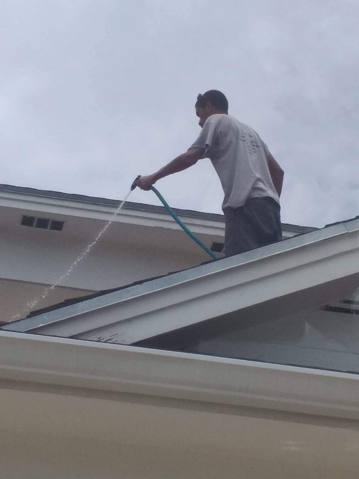 D.B. Clean242 technician soft washing a home roof with a low-pressure rinse in The Bahamas